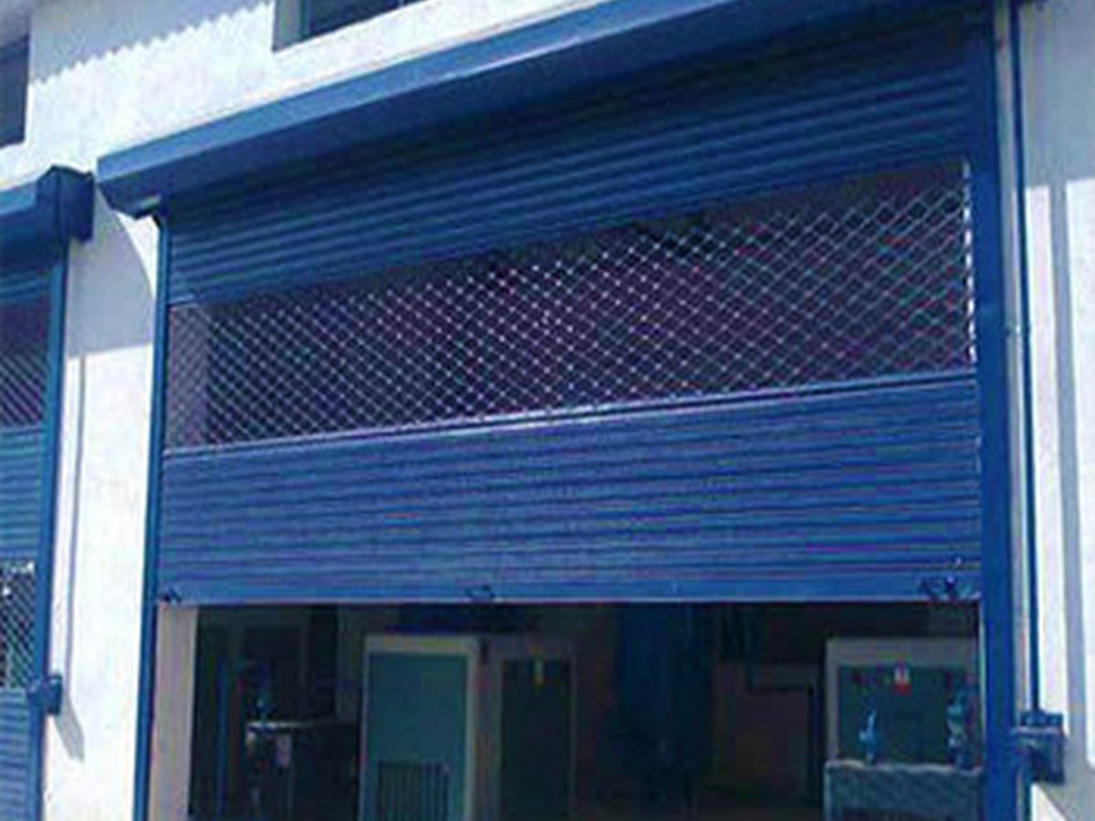 Shopfront shutter combining solid laths below with a grill section above